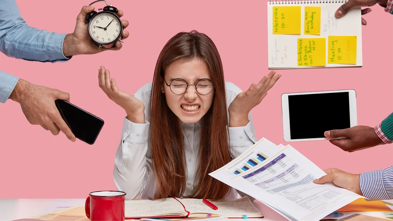 Stressed nonprofit professional overwhelmed by multiple tasks including clock, phone, tablet, calendar, and reports