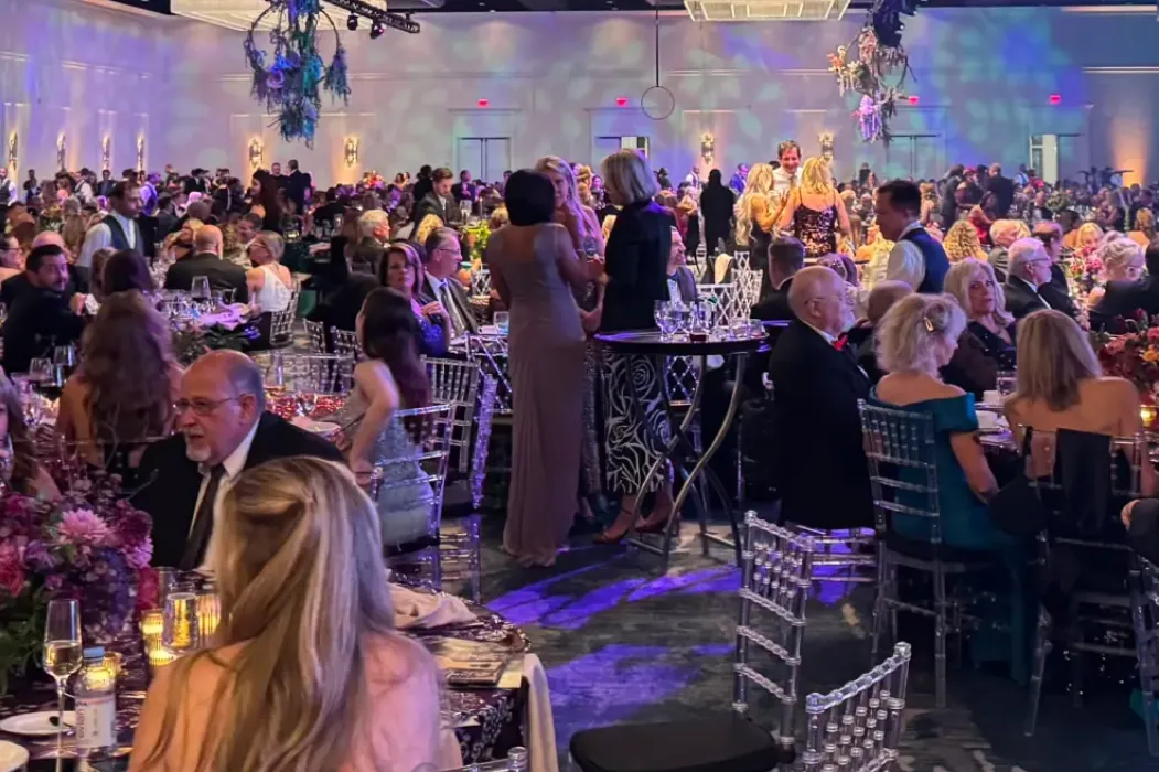 Guests dressed in formal attire sitting at round tables during the Kids Beating Cancer gala event in a large ballroom.